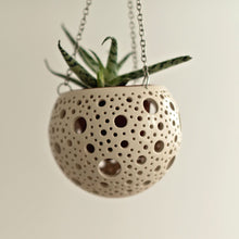 Load image into Gallery viewer, Enjoy this pot as either a planter or a hanging candle holder - the choice is yours! The detailed designs are carved by hand into the pottery and either allow air to circulate to your plant or cast fascinating patterns if you use it as a candle holder!