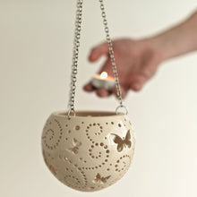Load image into Gallery viewer, Enjoy this pot as either a planter or a hanging candle holder - the choice is yours! The detailed designs are carved by hand into the pottery and either allow air to circulate to your plant or cast fascinating patterns if you use it as a candle holder!